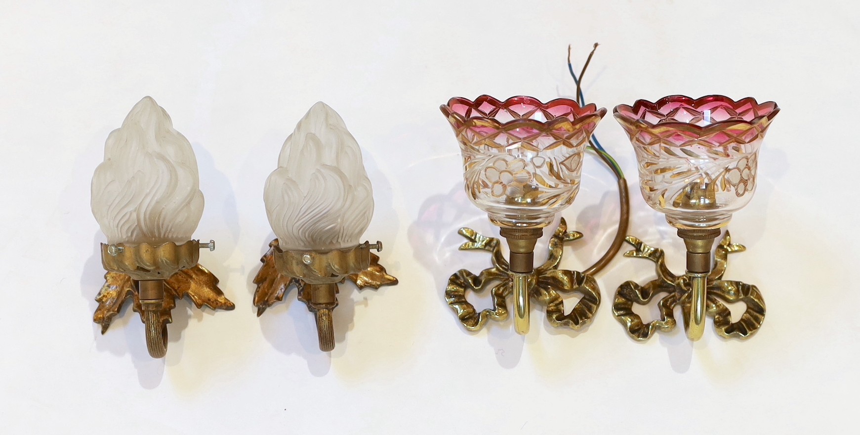 A pair of 1920s brass wall lights with frosted flame glass shades and a pair of brass ribbon back wall lights with lustre shades, height 14cm & height 12cm